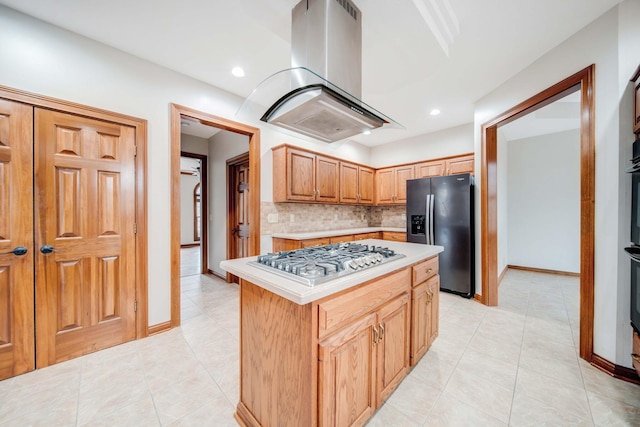 kitchen with light tile patterned flooring, tasteful backsplash, island range hood, a kitchen island, and stainless steel appliances