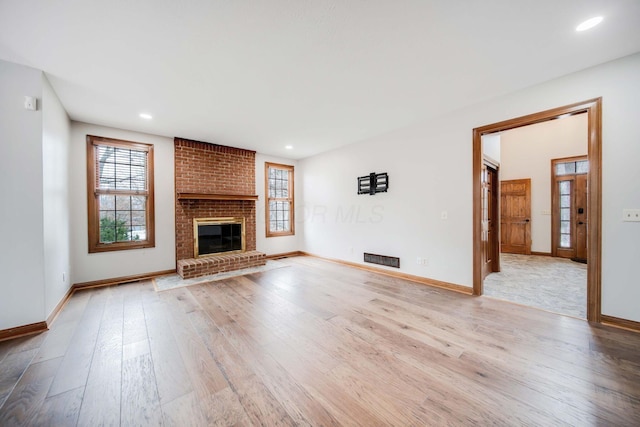 unfurnished living room featuring a brick fireplace and light hardwood / wood-style flooring