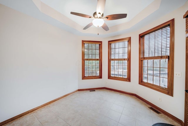 tiled spare room with a tray ceiling and ceiling fan