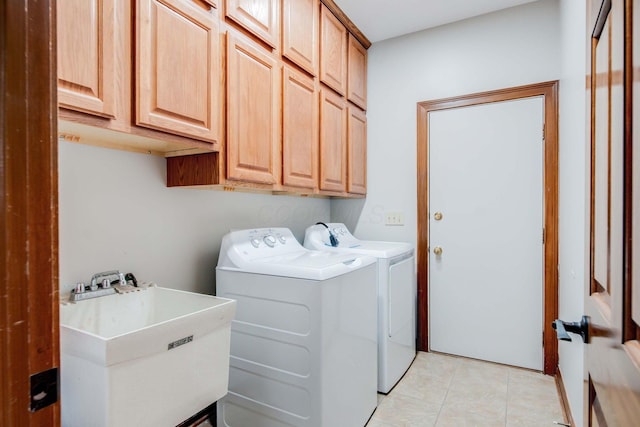 laundry area with cabinets, washer and clothes dryer, sink, and light tile patterned floors