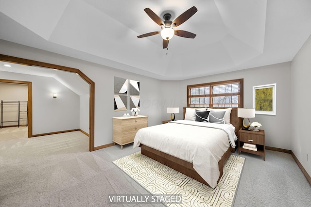 carpeted bedroom featuring ceiling fan and a raised ceiling