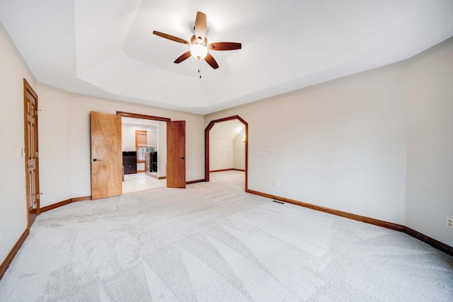 carpeted empty room with a tray ceiling and ceiling fan