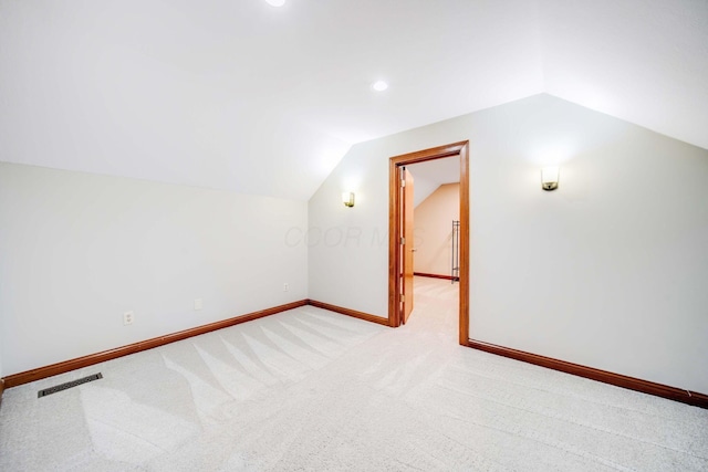 additional living space featuring vaulted ceiling and light carpet