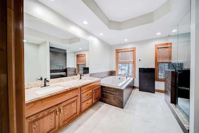 bathroom with vanity, a raised ceiling, and separate shower and tub