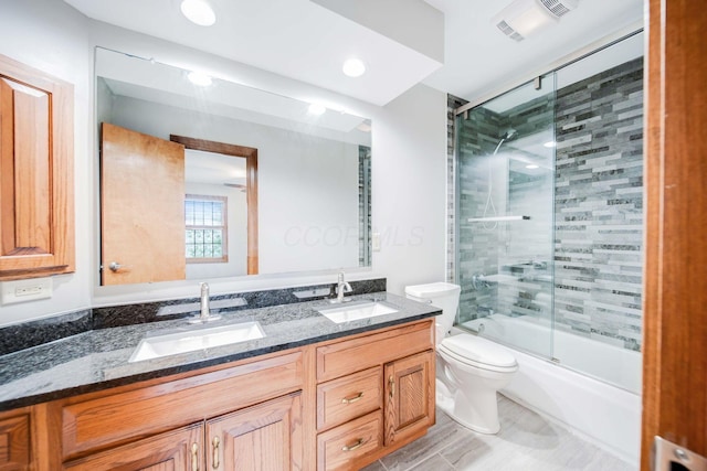 full bathroom featuring vanity, shower / bath combination with glass door, and toilet