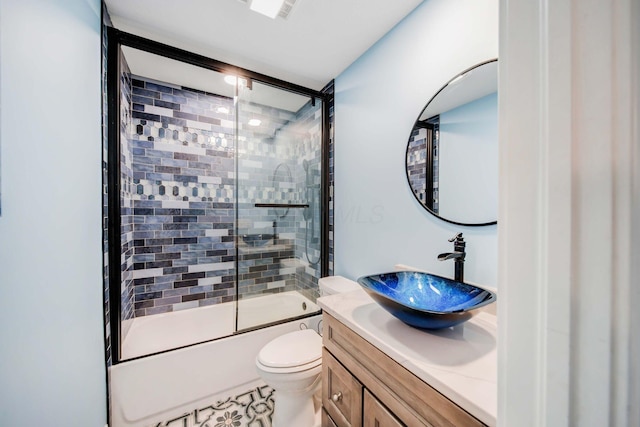 full bathroom featuring enclosed tub / shower combo, vanity, and toilet