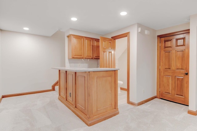 kitchen featuring kitchen peninsula, light carpet, and light brown cabinets