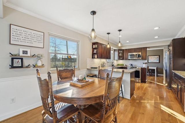 dining room with ornamental molding, sink, and light hardwood / wood-style floors