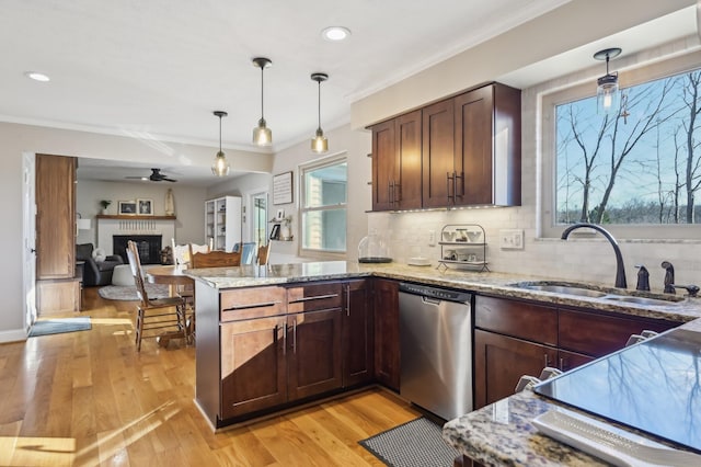 kitchen with pendant lighting, sink, light stone countertops, and dishwasher