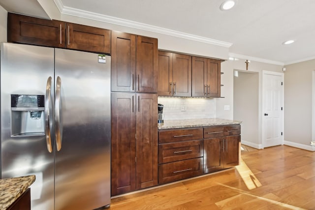 kitchen with crown molding, stainless steel fridge, and light stone counters