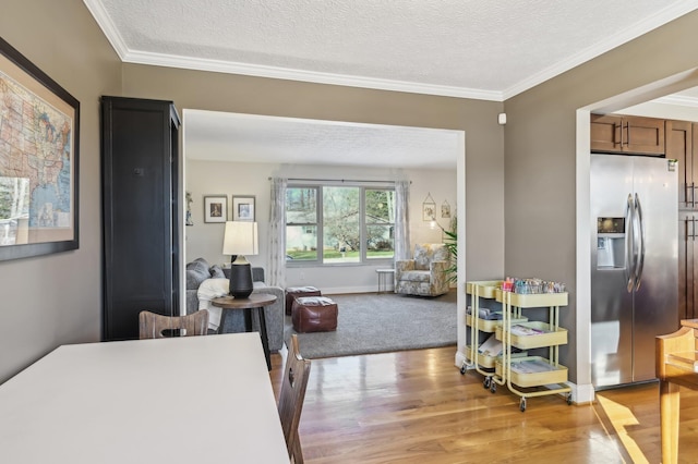 dining room featuring crown molding, light hardwood / wood-style flooring, and a textured ceiling