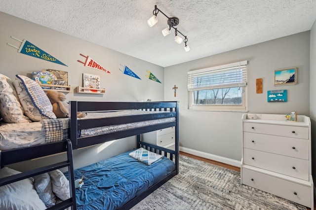 bedroom featuring wood-type flooring, rail lighting, and a textured ceiling