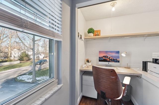 home office with dark wood-type flooring, built in desk, and a textured ceiling