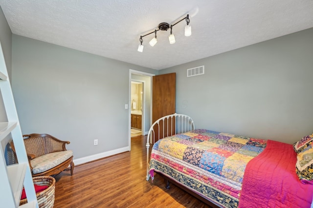 bedroom featuring hardwood / wood-style flooring, track lighting, and a textured ceiling