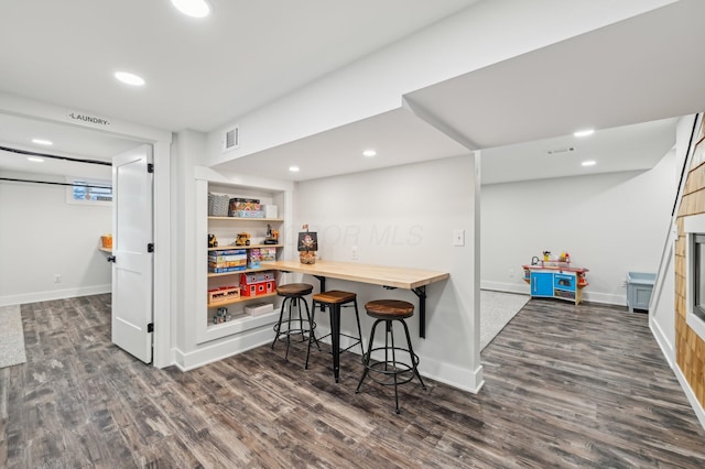 kitchen featuring butcher block counters, dark wood-type flooring, and a kitchen breakfast bar