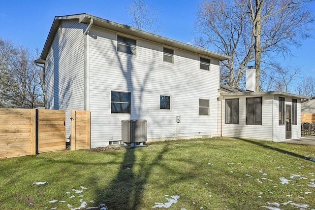 back of property with central AC, a sunroom, and a lawn