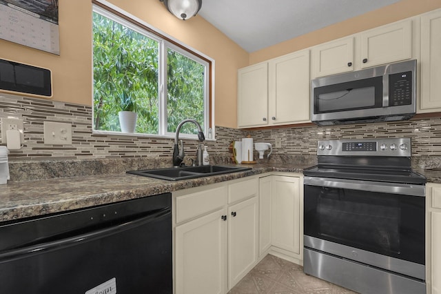 kitchen with sink, appliances with stainless steel finishes, white cabinetry, backsplash, and dark stone counters