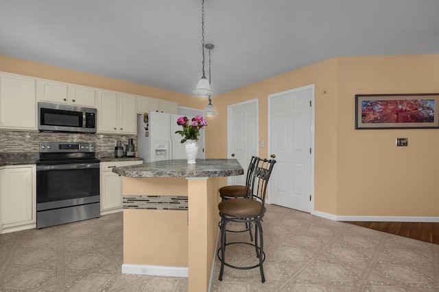 kitchen with hanging light fixtures, appliances with stainless steel finishes, a kitchen island, white cabinets, and backsplash