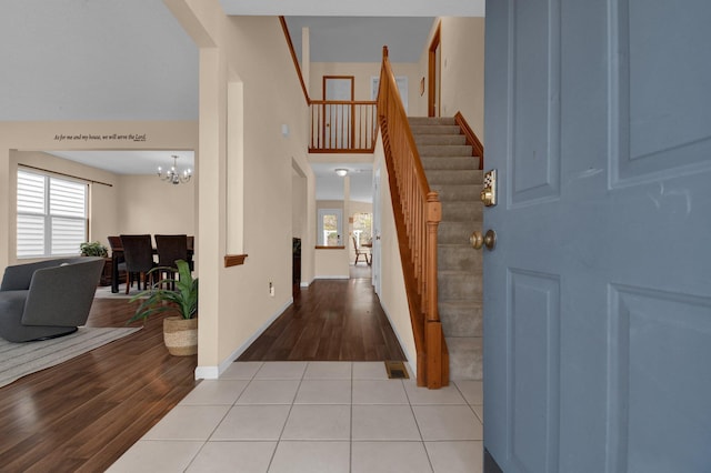 tiled entryway with an inviting chandelier and a high ceiling