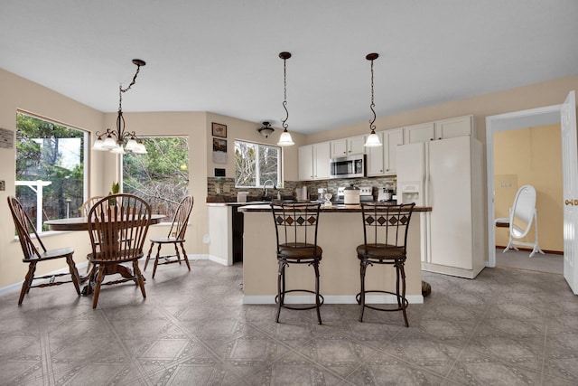 kitchen with white cabinetry, appliances with stainless steel finishes, decorative light fixtures, and plenty of natural light