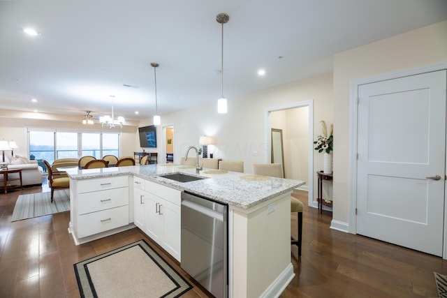 kitchen with sink, a breakfast bar area, dishwasher, pendant lighting, and white cabinets