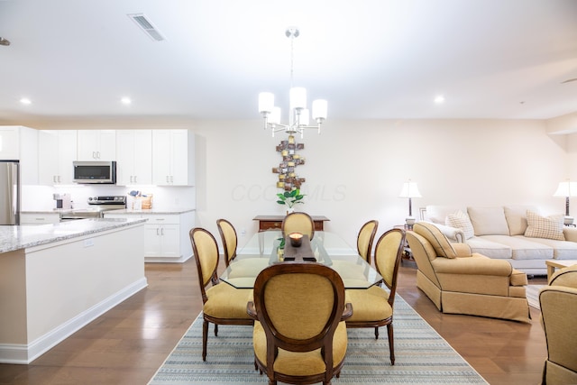 dining area with dark hardwood / wood-style floors and a notable chandelier