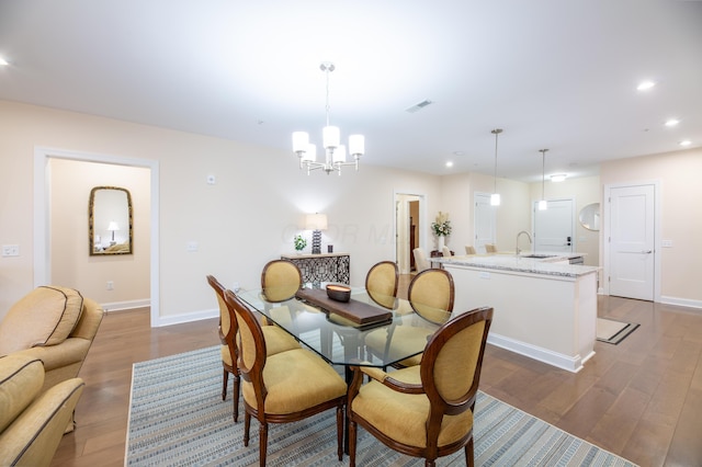 dining room with sink, hardwood / wood-style floors, and an inviting chandelier