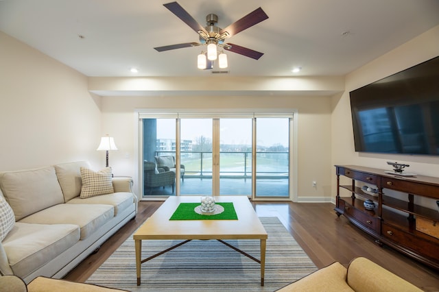 living room featuring dark wood-type flooring and ceiling fan