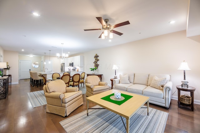 living room with ceiling fan with notable chandelier and dark hardwood / wood-style floors