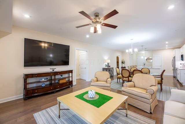 living room with dark hardwood / wood-style flooring and ceiling fan with notable chandelier