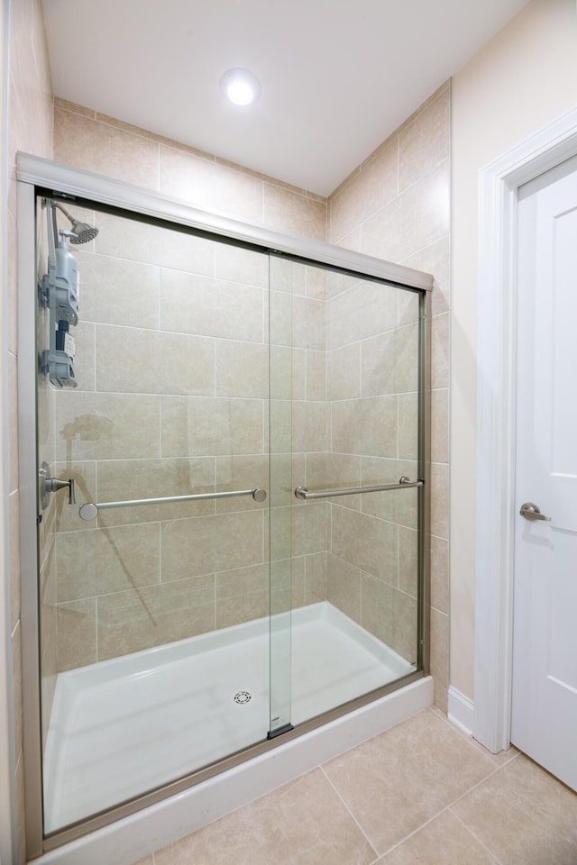 bathroom with a shower with door and tile patterned floors