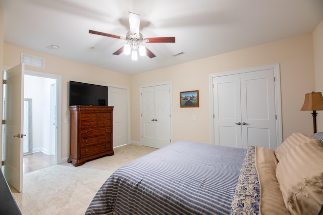 carpeted bedroom with ceiling fan and two closets