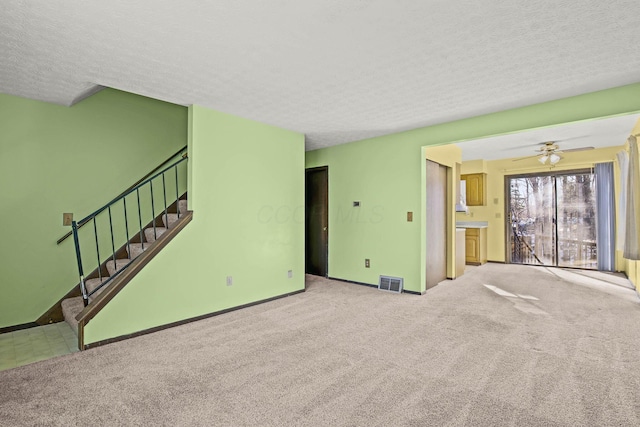 unfurnished living room with ceiling fan, light carpet, and a textured ceiling