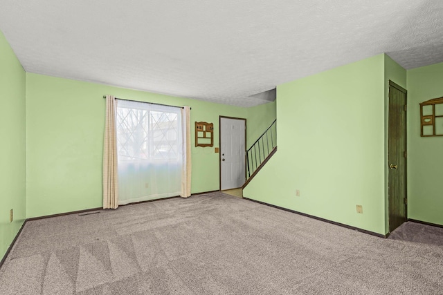 carpeted spare room with a textured ceiling