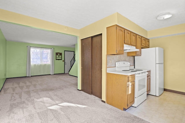 kitchen with white appliances, light colored carpet, and a textured ceiling