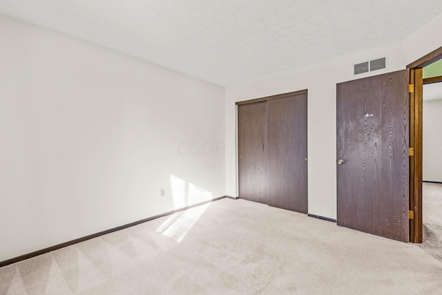 unfurnished bedroom with light carpet and a textured ceiling