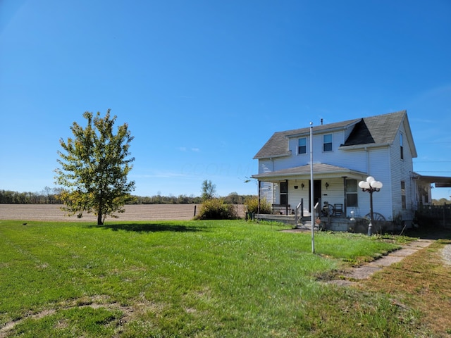 rear view of property featuring a yard and covered porch