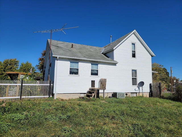 back of property with central AC unit and a lawn