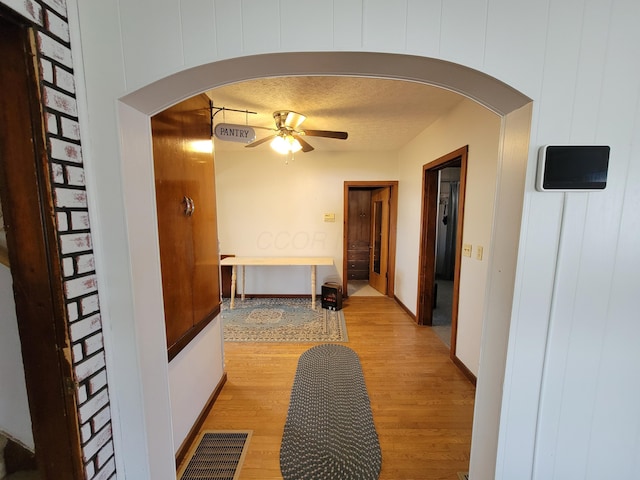 corridor with a textured ceiling and light wood-type flooring