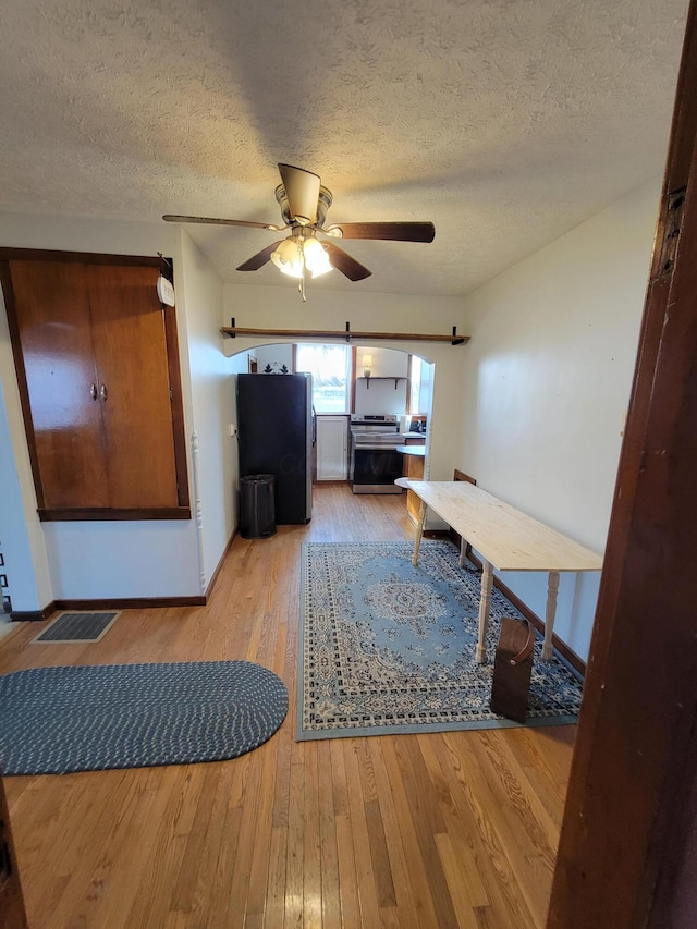 interior space with ceiling fan, light hardwood / wood-style floors, and a textured ceiling