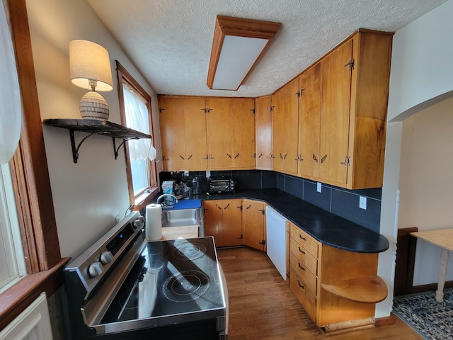 kitchen with sink, dishwasher, stove, backsplash, and hardwood / wood-style floors