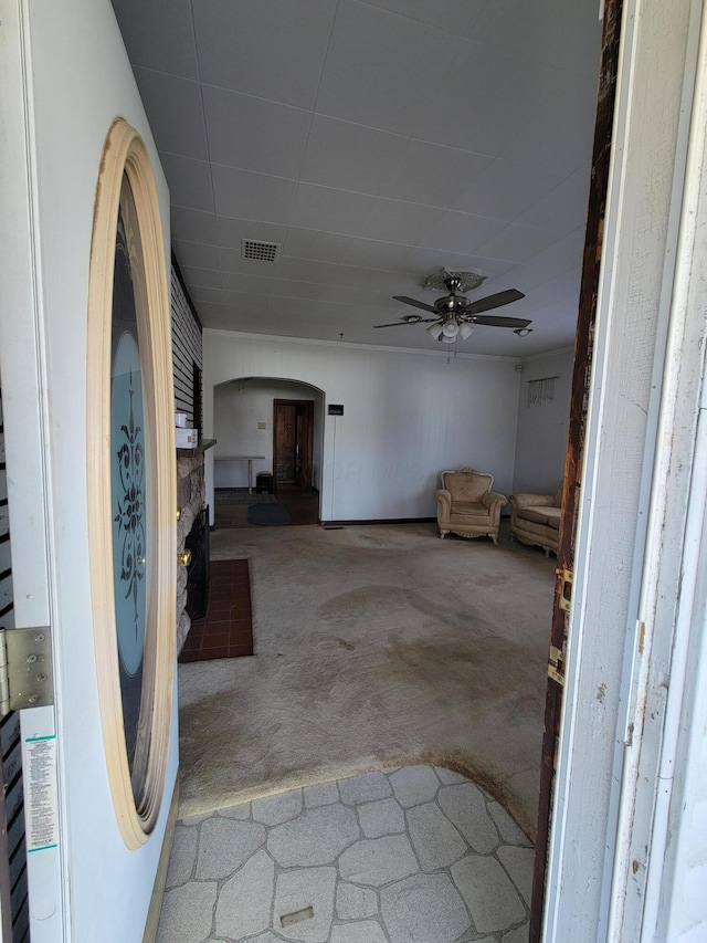 interior space with a stone fireplace, carpet floors, and ceiling fan