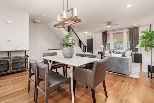 dining room with ceiling fan with notable chandelier and light hardwood / wood-style flooring