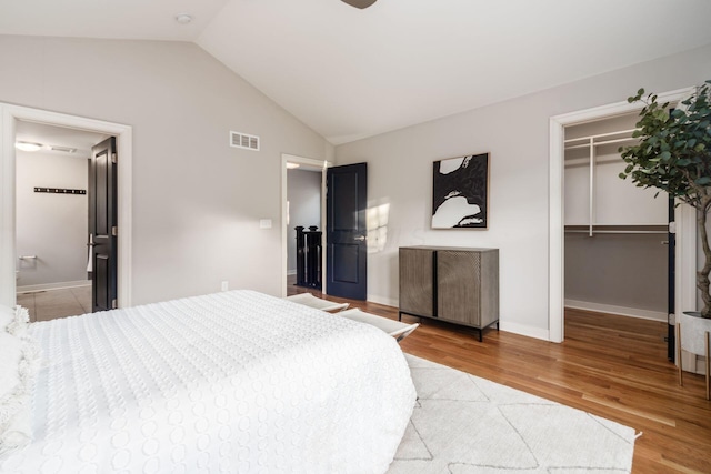 bedroom featuring ensuite bathroom, wood-type flooring, lofted ceiling, a spacious closet, and a closet