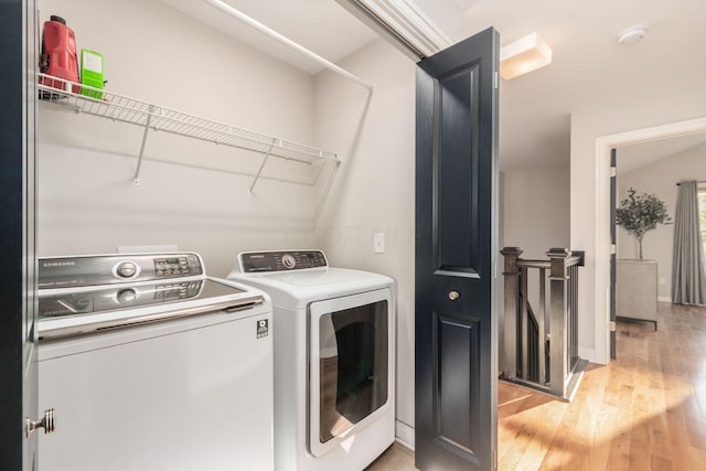 clothes washing area with washer and clothes dryer and light wood-type flooring