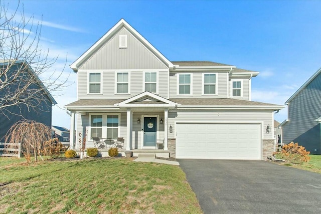 view of front of home featuring a garage, covered porch, and a front yard