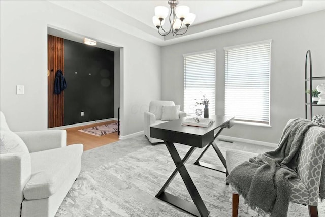 office area featuring a notable chandelier and a tray ceiling