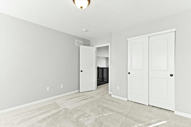 unfurnished bedroom featuring light colored carpet and a closet