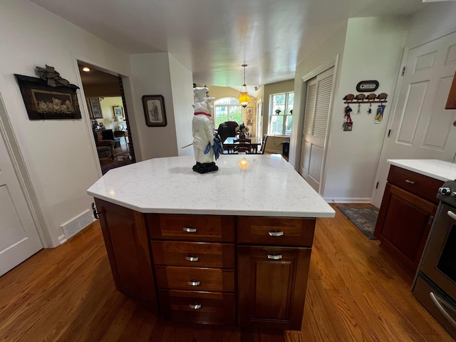 kitchen featuring a center island, pendant lighting, stainless steel range oven, and dark hardwood / wood-style flooring