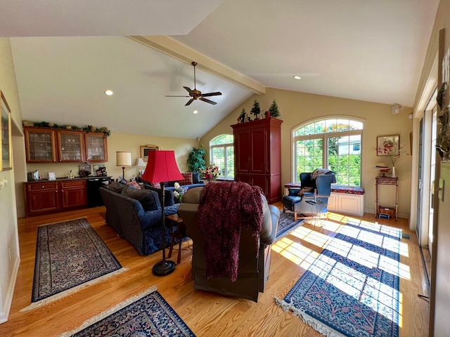 living room with lofted ceiling with beams, ceiling fan, and light wood-type flooring